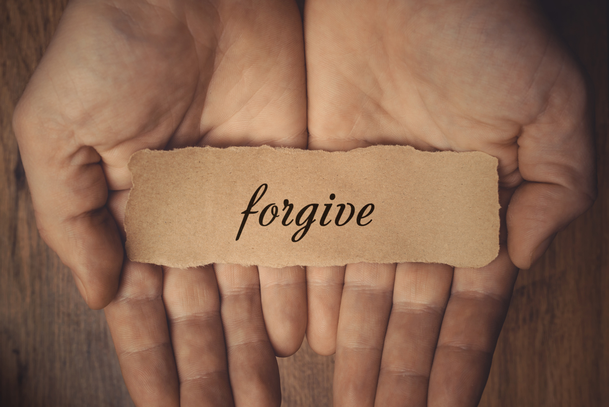 open hands holding paper that says forgive